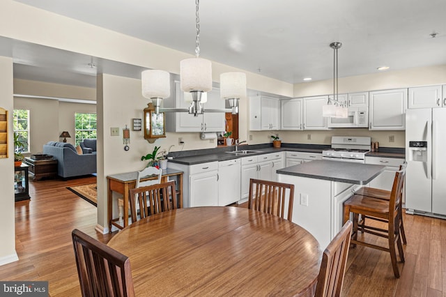 kitchen with white appliances, a sink, dark countertops, recessed lighting, and white cabinetry