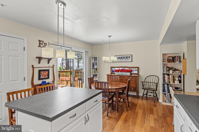 kitchen featuring dark countertops, light wood-type flooring, white cabinets, a chandelier, and pendant lighting