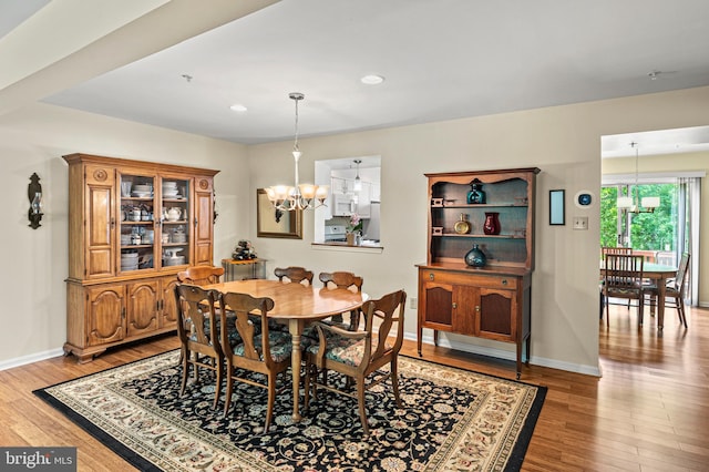 dining area featuring a chandelier, wood finished floors, baseboards, and recessed lighting