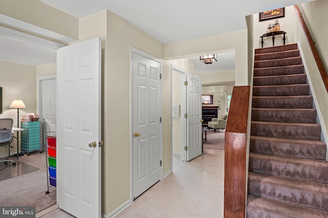 staircase featuring baseboards, a chandelier, and tile patterned floors