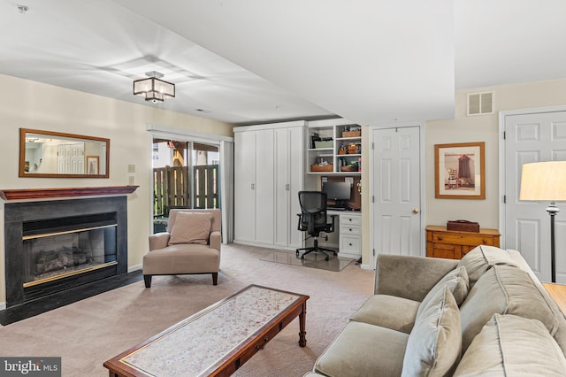 living area featuring a desk, carpet flooring, and a fireplace with flush hearth