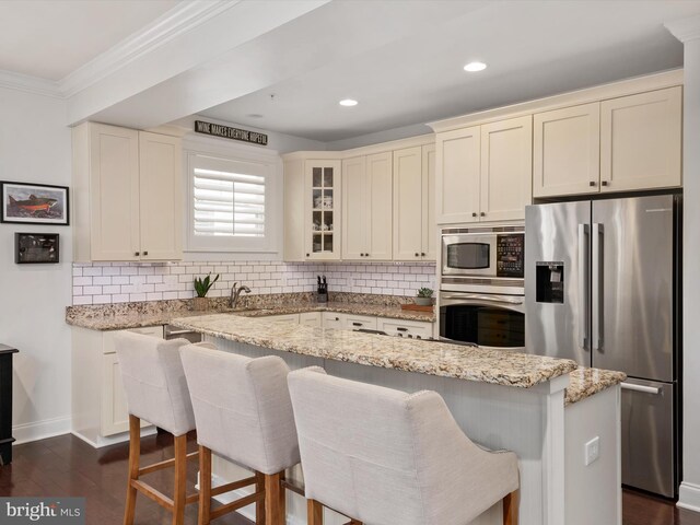 816 Bay Ridge Ave, Annapolis, MD 21403 - kitchen featuring appliances with stainless steel finishes, ornamental molding, decorative backsplash, glass insert cabinets, and a kitchen breakfast bar