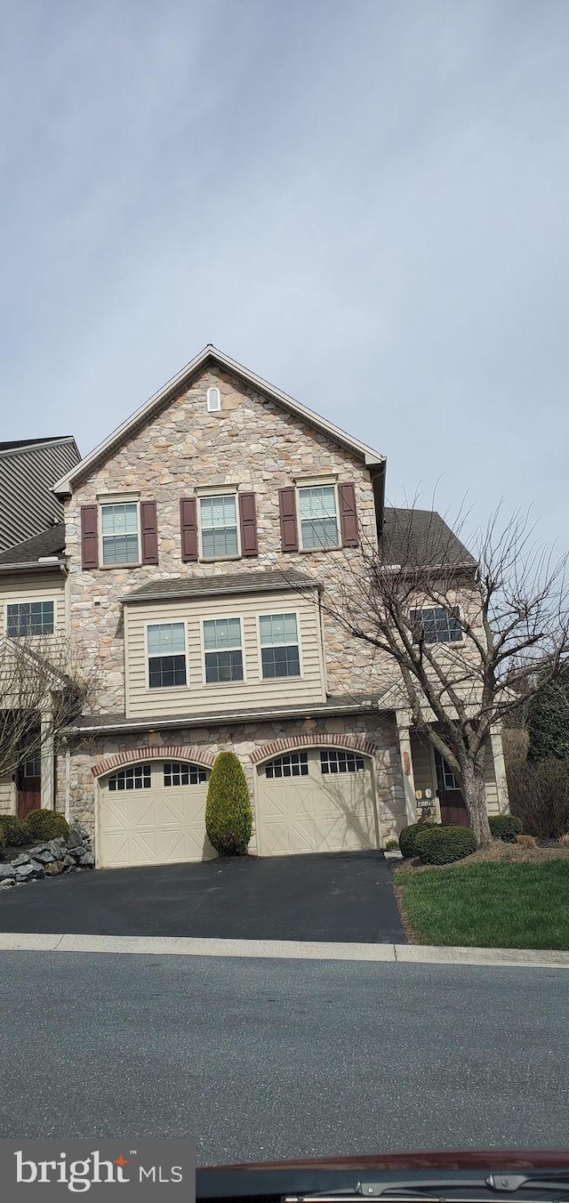 view of front facade with stone siding, asphalt driveway, and an attached garage