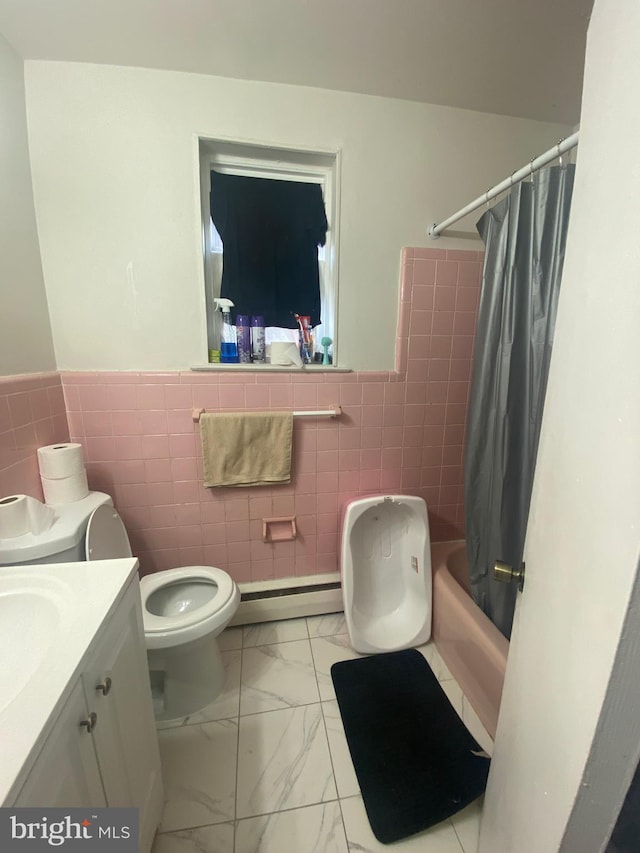 bathroom with tile walls, baseboard heating, marble finish flooring, toilet, and vanity