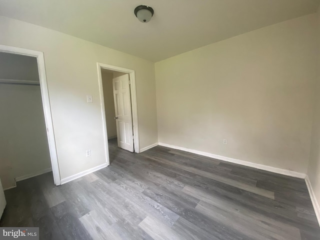 unfurnished bedroom featuring dark wood-type flooring, baseboards, and a closet