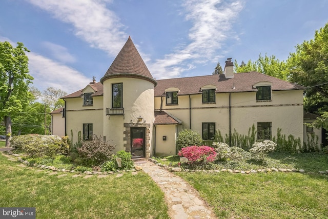 view of front of property featuring stucco siding, a chimney, a front yard, and a shingled roof