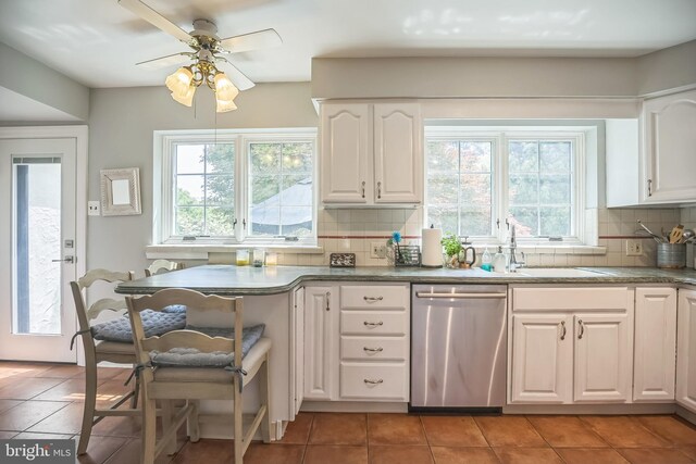 kitchen featuring stainless steel dishwasher, backsplash, light tile patterned flooring, and white cabinetry