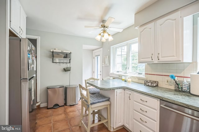kitchen featuring appliances with stainless steel finishes, a ceiling fan, decorative backsplash, white cabinetry, and a peninsula
