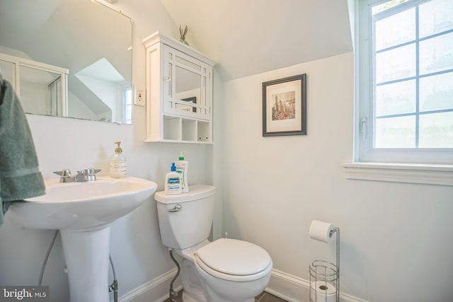 bathroom featuring plenty of natural light, toilet, baseboards, lofted ceiling, and a sink