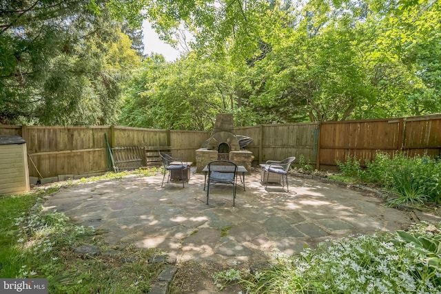 view of patio / terrace featuring a fenced backyard and an outdoor stone fireplace
