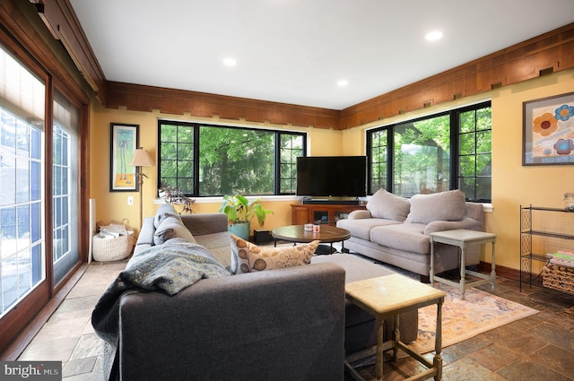 living room with stone tile floors, recessed lighting, baseboards, and crown molding