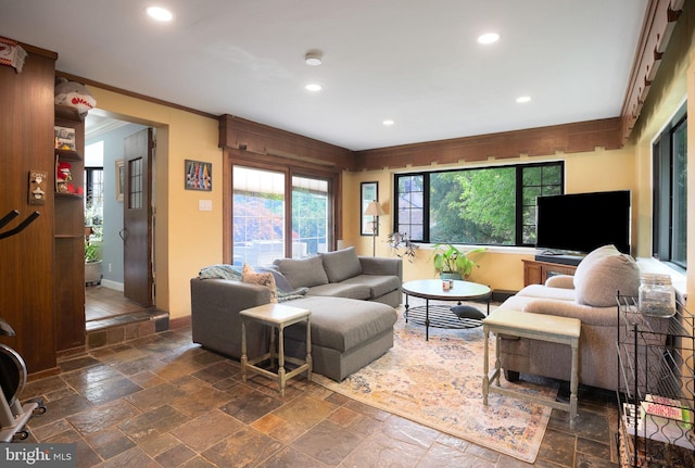 living area featuring stone tile floors, crown molding, recessed lighting, and baseboards
