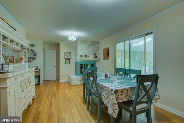 8406 Cedar Ln, King George, VA 22485 - dining room with crown molding, light wood-style floors, a textured ceiling, baseboards, and a brick fireplace
