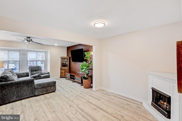 384 Bolton Rd, East Windsor, NJ 08520 - living room featuring a lit fireplace, light wood-style flooring, a ceiling fan, and baseboards