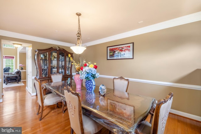 dining space with light wood-type flooring, baseboards, and crown molding