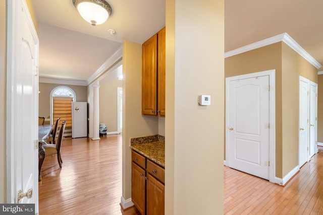 hallway with crown molding, light wood-type flooring, decorative columns, and baseboards