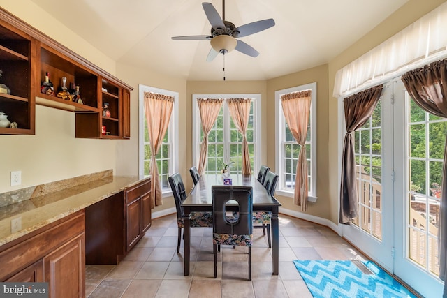 dining room with healthy amount of natural light, light tile patterned flooring, a ceiling fan, and baseboards
