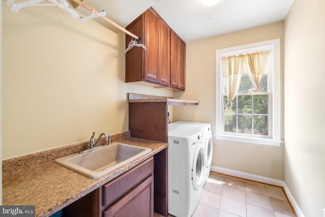 clothes washing area with washing machine and dryer, baseboards, light tile patterned floors, and cabinet space
