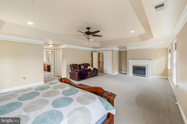 bedroom featuring a tray ceiling, light colored carpet, baseboards, a glass covered fireplace, and recessed lighting