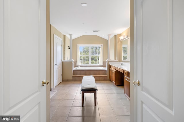 bathroom featuring ornate columns, lofted ceiling, vanity, a garden tub, and tile patterned floors