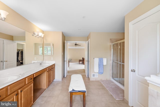bathroom featuring a stall shower, double vanity, tile patterned flooring, a ceiling fan, and a spacious closet