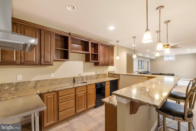 kitchen featuring wall chimney range hood, open shelves, a sink, ceiling fan, and a breakfast bar