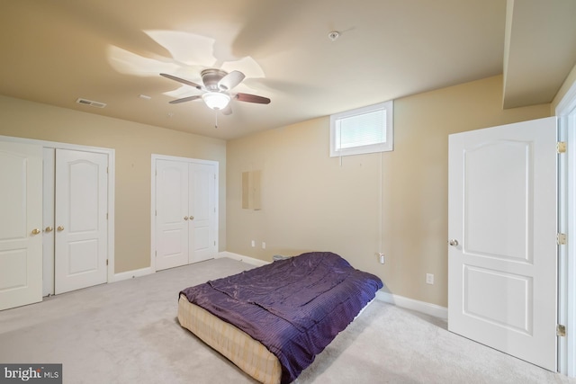 carpeted bedroom featuring two closets, baseboards, and a ceiling fan