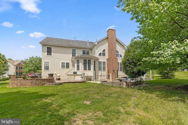 rear view of property with a patio area, a chimney, and a yard