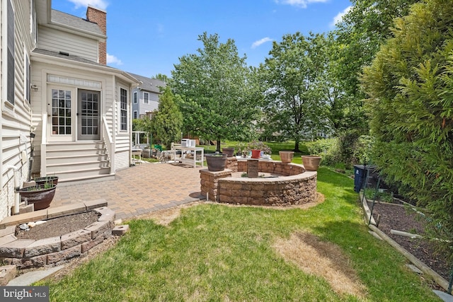 view of green lawn with a patio, entry steps, and a fire pit