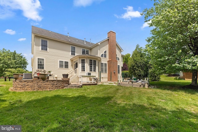 rear view of property featuring a chimney, cooling unit, a patio, a yard, and entry steps