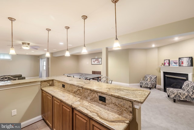 kitchen featuring open floor plan, light stone countertops, ceiling fan, a glass covered fireplace, and recessed lighting