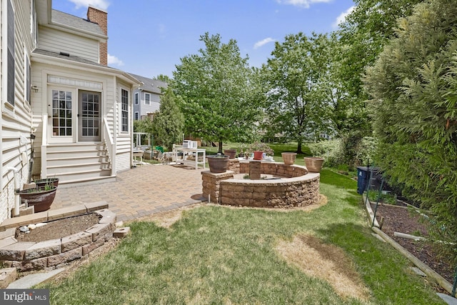 view of grassy yard with a patio area and entry steps