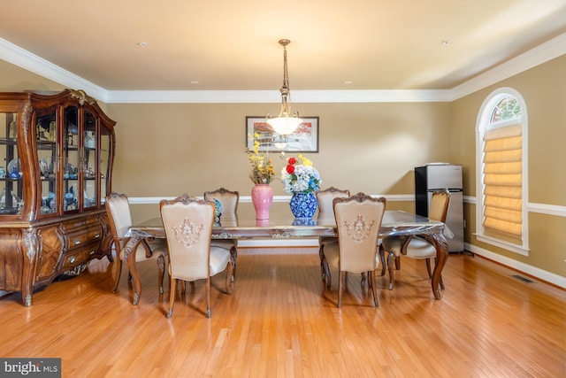 dining space with wood finished floors, baseboards, and crown molding