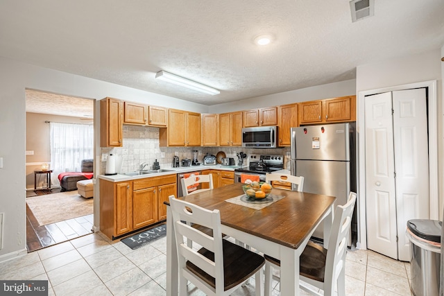 9910 Warwick Pl, Fredericksburg, VA 22408 - kitchen with stainless steel appliances, a sink, light tile patterned floors, tasteful backsplash, and light countertops
