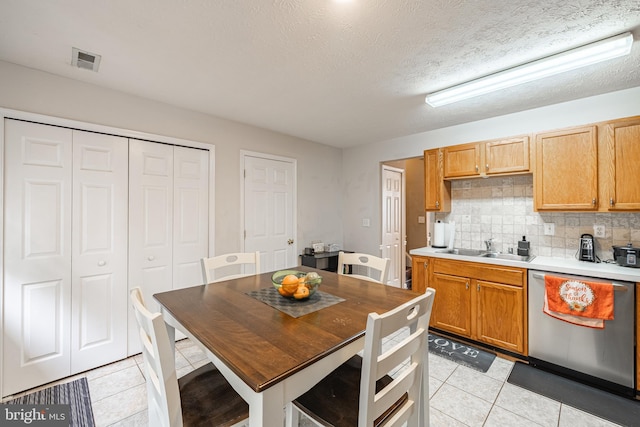 9910 Warwick Pl, Fredericksburg, VA 22408 - kitchen featuring stainless steel dishwasher, light tile patterned floors, a sink, tasteful backsplash, and light countertops