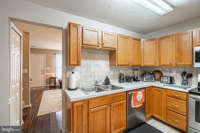 9910 Warwick Pl, Fredericksburg, VA 22408 - kitchen featuring appliances with stainless steel finishes, a sink, a textured ceiling, light countertops, and decorative backsplash