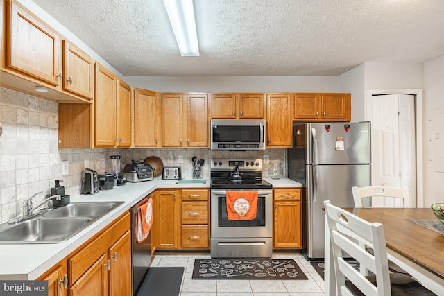 9910 Warwick Pl, Fredericksburg, VA 22408 - kitchen featuring stainless steel appliances, a sink, light tile patterned floors, backsplash, and a textured ceiling