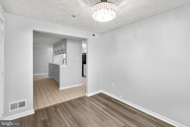 1476 Greenbriar Cir Unit 1-1476, Pikesville, MD 21208 - unfurnished room featuring dark wood finished floors, a chandelier, a textured ceiling, and baseboards