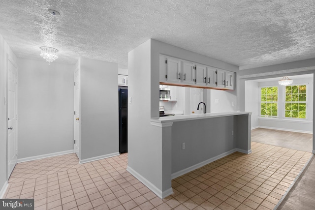 1476 Greenbriar Cir Unit 1-1476, Pikesville, MD 21208 - kitchen with light countertops, stainless steel appliances, white cabinetry, a sink, and baseboards