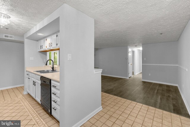 1476 Greenbriar Cir Unit 1-1476, Pikesville, MD 21208 - kitchen with black dishwasher, a sink, a textured ceiling, white cabinetry, and light tile patterned floors