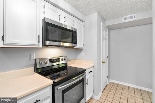 1476 Greenbriar Cir Unit 1-1476, Pikesville, MD 21208 - kitchen featuring stainless steel appliances, white cabinetry, light countertops, light tile patterned floors, and baseboards