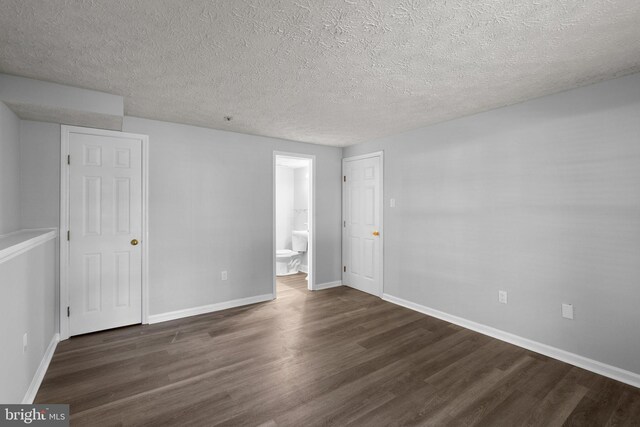 1476 Greenbriar Cir Unit 1-1476, Pikesville, MD 21208 - unfurnished bedroom with dark wood-style flooring, baseboards, a textured ceiling, and connected bathroom