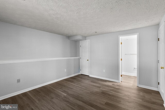 1476 Greenbriar Cir Unit 1-1476, Pikesville, MD 21208 - unfurnished bedroom with dark wood-style flooring, a textured ceiling, baseboards, and connected bathroom