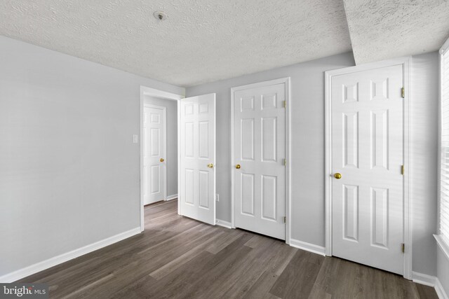 1476 Greenbriar Cir Unit 1-1476, Pikesville, MD 21208 - unfurnished bedroom featuring dark wood finished floors, baseboards, and a textured ceiling