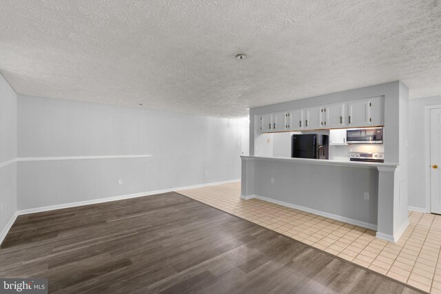 1476 Greenbriar Cir Unit 1-1476, Pikesville, MD 21208 - kitchen with appliances with stainless steel finishes, wood finished floors, open floor plan, a textured ceiling, and light countertops