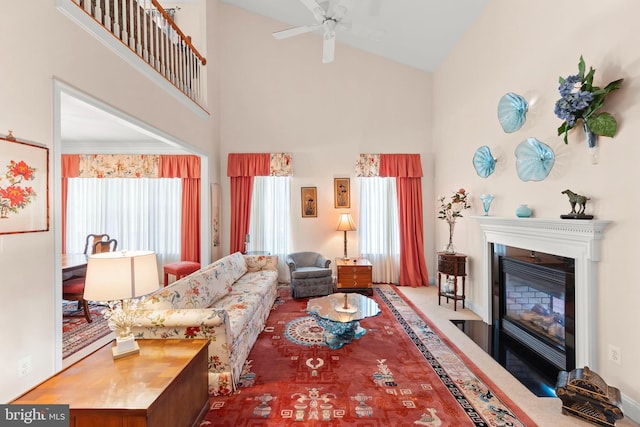living area with high vaulted ceiling, a fireplace with flush hearth, and ceiling fan