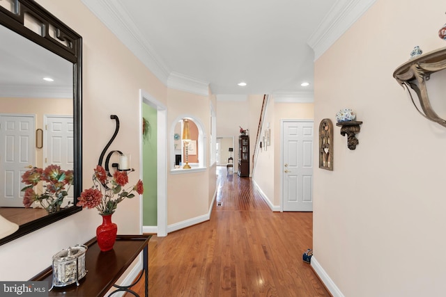 corridor featuring ornamental molding, light wood finished floors, baseboards, and recessed lighting