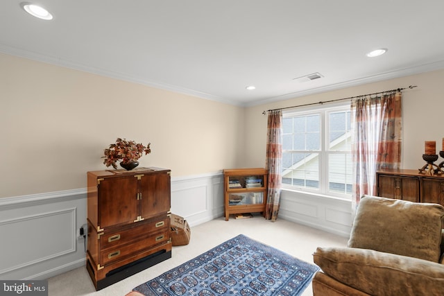 living area featuring wainscoting, ornamental molding, light colored carpet, a decorative wall, and recessed lighting