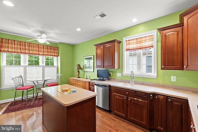 kitchen with dishwasher, a sink, a ceiling fan, light countertops, and a center island
