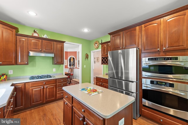 kitchen featuring appliances with stainless steel finishes, under cabinet range hood, light countertops, light wood-style floors, and recessed lighting